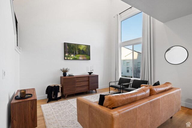 13077 S Keegan Dr, Herriman, UT 84096 - living room featuring baseboards, light wood finished floors, and a towering ceiling