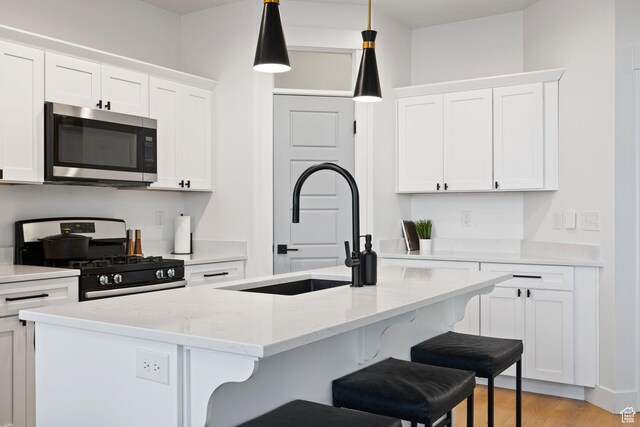 13077 S Keegan Dr, Herriman, UT 84096 - kitchen with a sink, white cabinetry, appliances with stainless steel finishes, and a kitchen bar