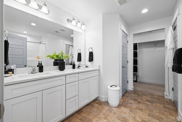13077 S Keegan Dr, Herriman, UT 84096 - bathroom featuring stone finish flooring, visible vents, a shower, a sink, and a spacious closet