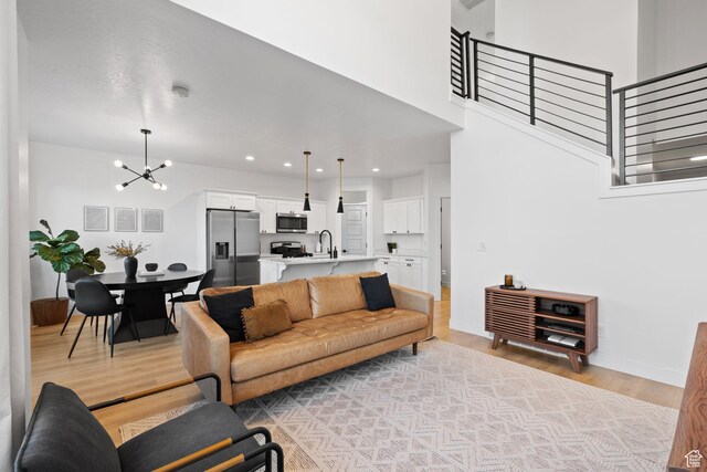 13077 S Keegan Dr, Herriman, UT 84096 - living area featuring stairway, baseboards, a chandelier, a high ceiling, and light wood-style flooring