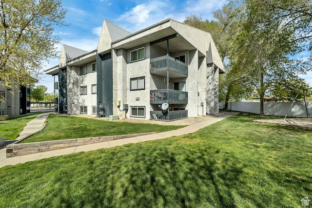 223 E Hill Ave Unit 6, Millcreek, UT 84107 - rear view of house with stucco siding, a balcony, a lawn, and central air condition unit