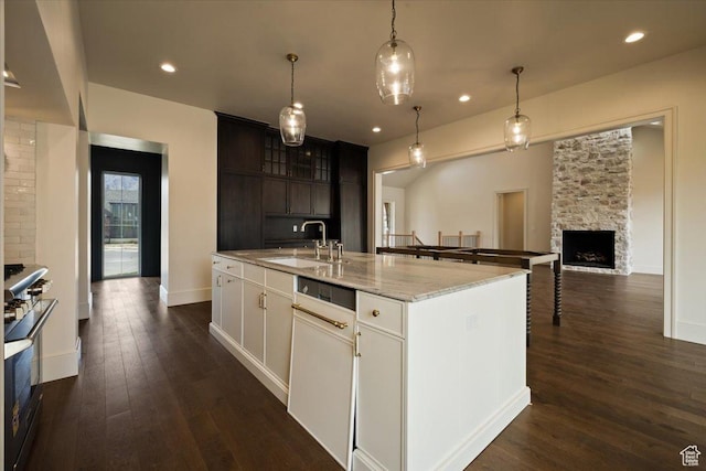 473 W 350 S Unit 31, Mapleton, UT 84664 - kitchen featuring light stone counters, a sink, a stone fireplace, an island with sink, and dark wood-style floors