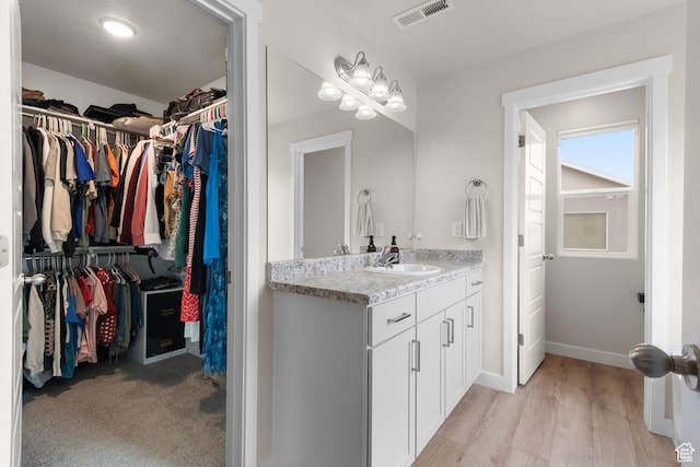 838 N Marble Rd, Tooele, UT 84074 - bathroom featuring visible vents, vanity, wood finished floors, baseboards, and a walk in closet