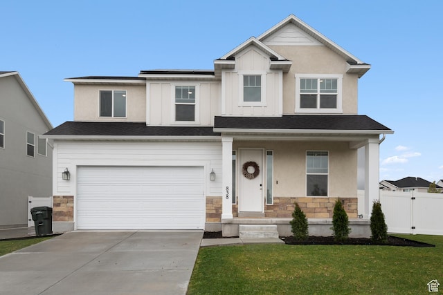 traditional home featuring a garage, a front yard, stone siding, concrete driveway, and a porch