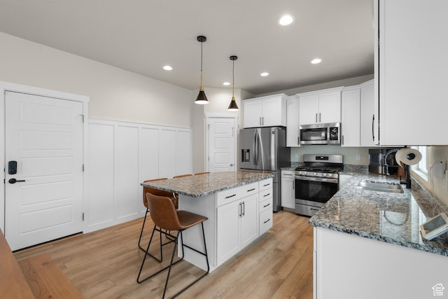 838 N Marble Rd, Tooele, UT 84074 - kitchen featuring appliances with stainless steel finishes, a wainscoted wall, a kitchen bar, and light wood-style flooring
