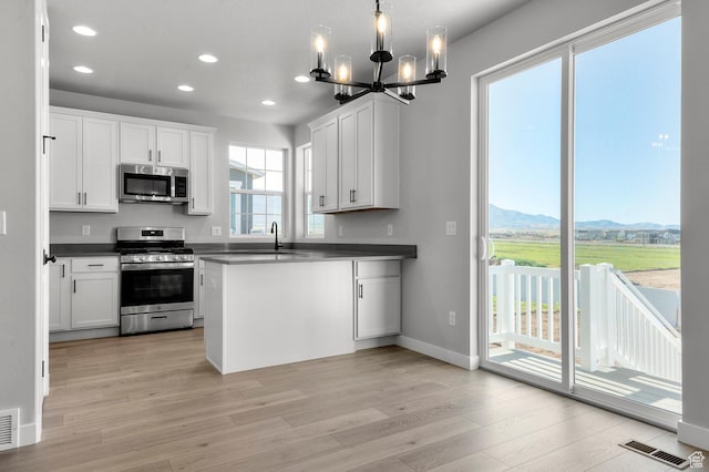 6628 W Spring Snow Ln, Herriman, UT 84096 - kitchen with appliances with stainless steel finishes, a chandelier, recessed lighting, light wood-style flooring, and dark countertops
