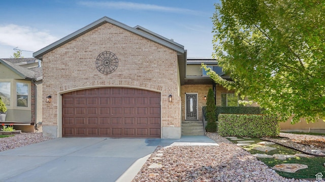 view of front facade with brick siding, a garage, and driveway