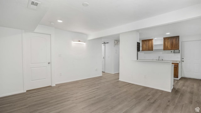 10674 S Pine Shadow Rd, South Jordan, UT 84009 - unfurnished living room with visible vents, light wood-style floors, baseboards, recessed lighting, and a sink
