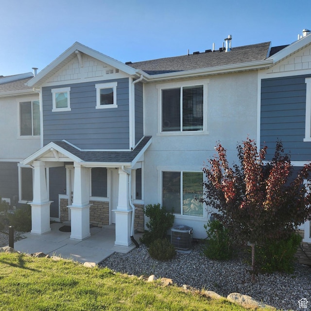 multi unit property featuring a shingled roof, central AC, stucco siding, and stone siding