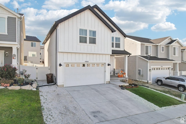 view of front facade featuring fence, a residential view, a garage, board and batten siding, and driveway