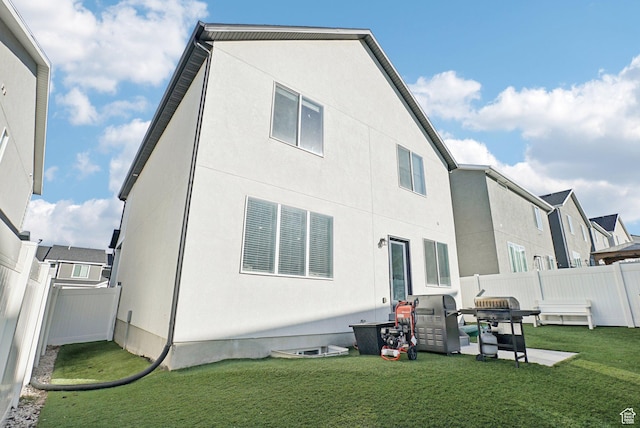 back of house with a lawn, a fenced backyard, and stucco siding