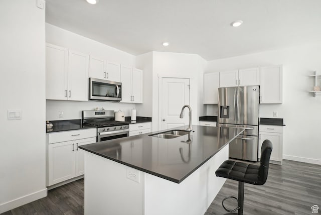 kitchen with stainless steel appliances, dark countertops, a breakfast bar, and a sink