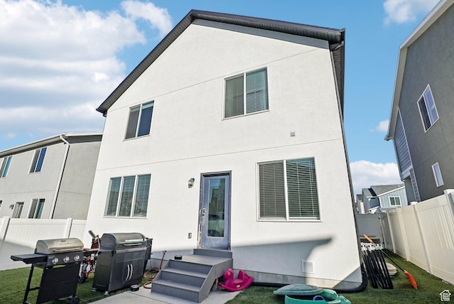 rear view of property featuring fence and stucco siding