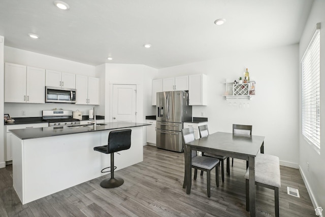 kitchen featuring visible vents, dark wood-style flooring, dark countertops, white cabinetry, and appliances with stainless steel finishes