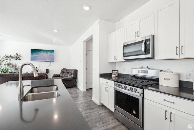 kitchen with stainless steel appliances, open floor plan, dark countertops, and a sink