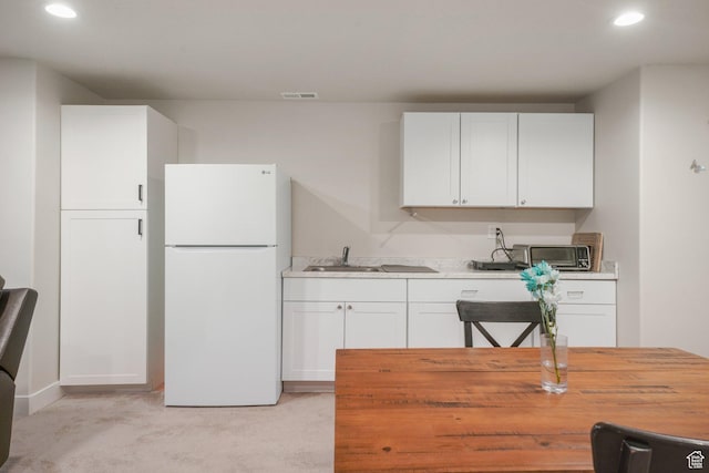 4576 W Sentry Dr, Riverton, UT 84096 - kitchen with freestanding refrigerator, a sink, recessed lighting, white cabinetry, and light carpet