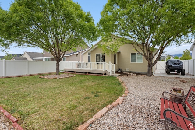 869 N Petro Dr W, Tooele, UT 84074 - back of property with a yard, a wooden deck, a fenced backyard, and stucco siding