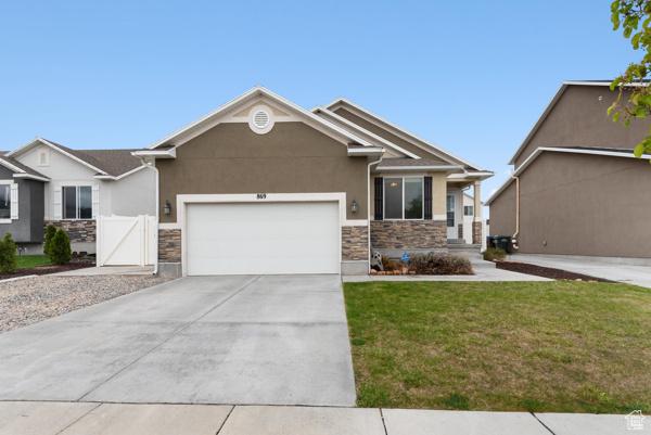 869 N Petro Dr W, Tooele, UT 84074 - view of front of property with a garage, driveway, stone siding, and stucco siding