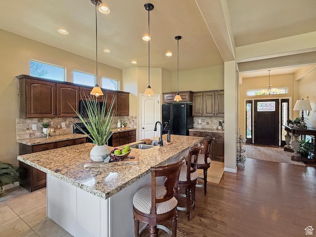 4116 N 800 W, Pleasant View, UT 84414 - kitchen featuring light stone countertops, black fridge, a sink, a kitchen island with sink, and tasteful backsplash