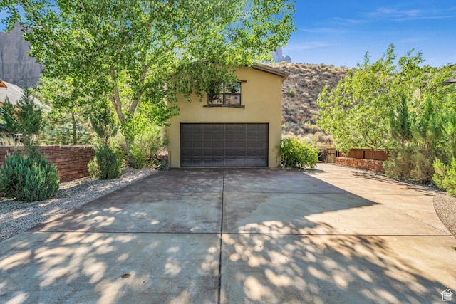 garage with concrete driveway and fence