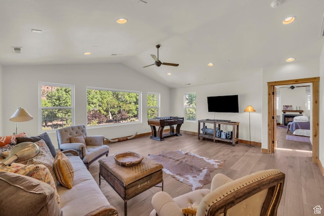 living area with baseboards, light wood-style flooring, ceiling fan, and lofted ceiling