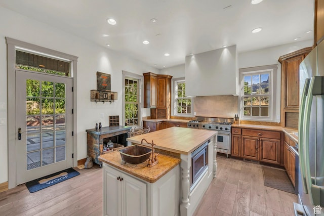 kitchen featuring a center island, ventilation hood, stainless steel appliances, and light wood-type flooring