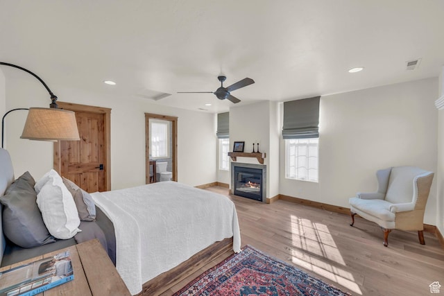 bedroom with visible vents, baseboards, a glass covered fireplace, recessed lighting, and light wood-style flooring