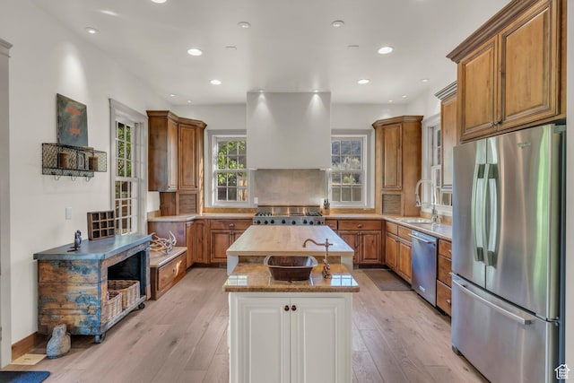 kitchen featuring appliances with stainless steel finishes, exhaust hood, brown cabinetry, and a kitchen island