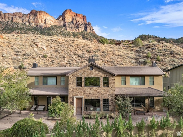 exterior space featuring a mountain view, a patio area, stucco siding, and a chimney