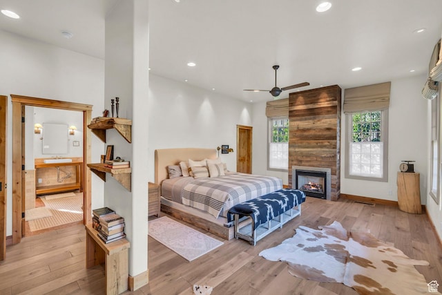 bedroom featuring wood-type flooring, recessed lighting, and a large fireplace