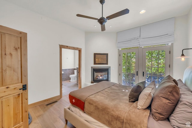 bedroom with a glass covered fireplace, access to exterior, recessed lighting, light wood-type flooring, and visible vents