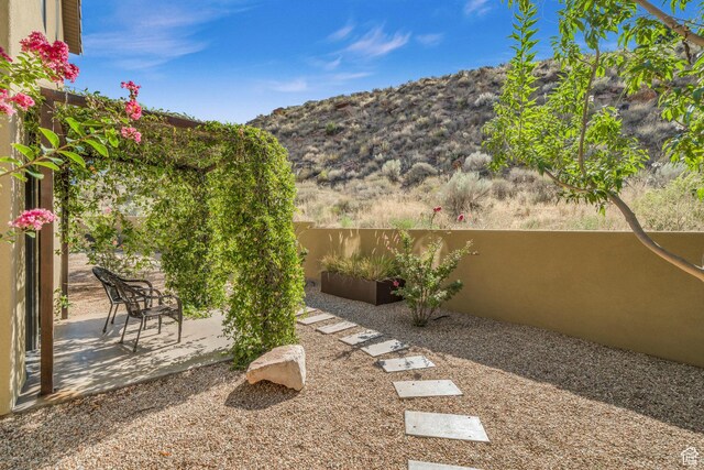 view of yard featuring a patio, a mountain view, and fence