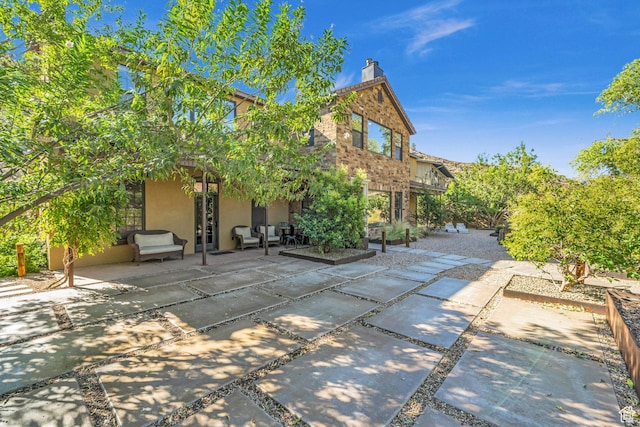 exterior space with outdoor lounge area, a patio, stucco siding, french doors, and a chimney