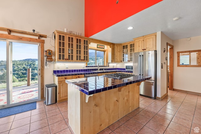 609 E 900 S, Stockton, UT 84071 - kitchen featuring light tile patterned flooring, appliances with stainless steel finishes, tile counters, a kitchen bar, and a kitchen island