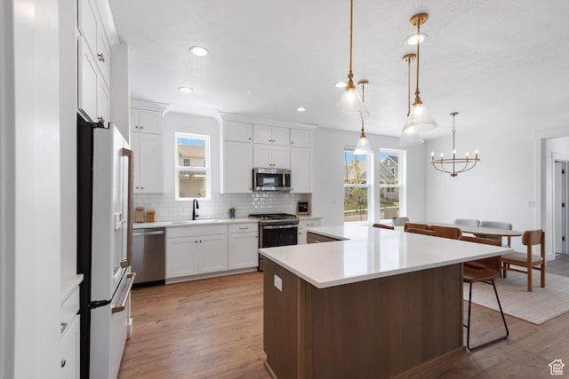 11254 S Bingham Rim Rd W, South Jordan, UT 84009 - kitchen featuring stainless steel appliances, a sink, backsplash, a center island, and light wood-style flooring