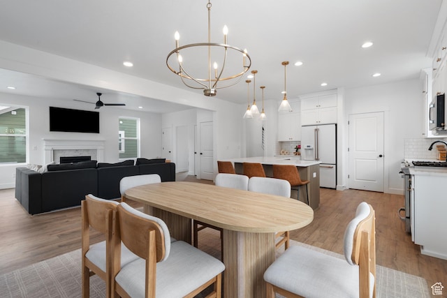 11254 S Bingham Rim Rd W, South Jordan, UT 84009 - dining space with a ceiling fan, light wood finished floors, a fireplace, recessed lighting, and a chandelier