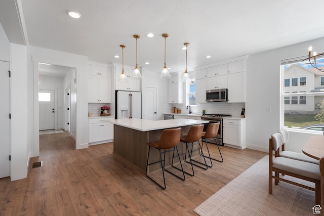 11254 S Bingham Rim Rd W, South Jordan, UT 84009 - kitchen with appliances with stainless steel finishes, tasteful backsplash, a kitchen island, white cabinets, and recessed lighting