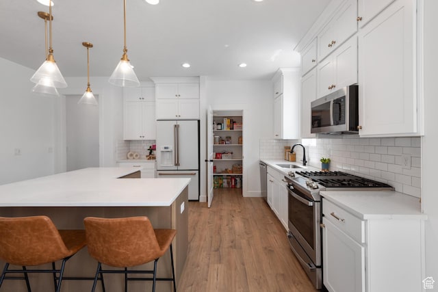 11254 S Bingham Rim Rd W, South Jordan, UT 84009 - kitchen featuring appliances with stainless steel finishes, a sink, decorative backsplash, a center island, and light wood-style flooring