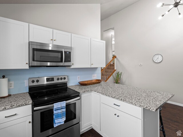 3855 W Elwood Way S, West Jordan, UT 84088 - kitchen featuring dark wood-style flooring, a peninsula, appliances with stainless steel finishes, and white cabinetry