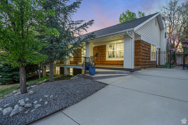 3273 E Bernada Dr, Salt Lake City, UT 84124 - property exterior at dusk with a shingled roof, fence, and covered porch