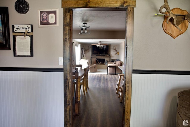 hallway featuring wood finished floors and a wainscoted wall