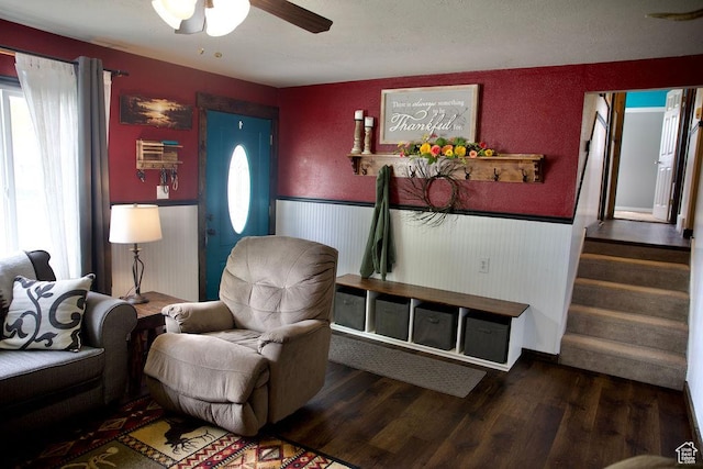 living room featuring a ceiling fan, wainscoting, stairs, and wood finished floors