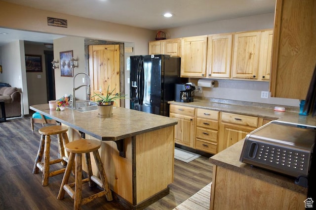 kitchen featuring a sink, light brown cabinets, a kitchen bar, and black refrigerator with ice dispenser