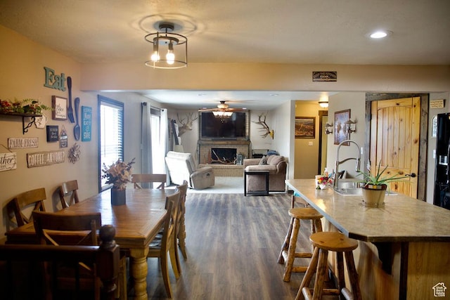 dining area featuring recessed lighting, a fireplace, a ceiling fan, and dark wood-style floors