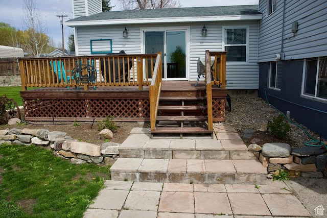 back of house with a deck, a chimney, and roof with shingles