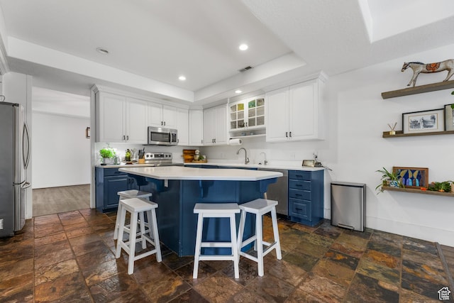 531 E Valley Dr, Heber City, UT 84032 - kitchen with appliances with stainless steel finishes, a kitchen breakfast bar, blue cabinets, visible vents, and stone tile flooring