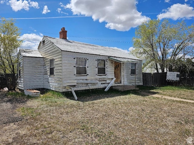 view of front of house featuring fence, a chimney, and a front lawn