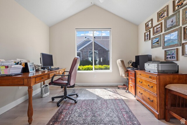 office space featuring baseboards, light wood-style flooring, and lofted ceiling