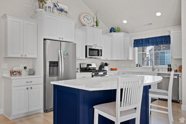 kitchen with a breakfast bar area, visible vents, lofted ceiling, stainless steel appliances, and white cabinetry