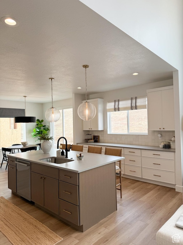 7648 S Iron Cyn Unit 341, West Jordan, UT 84081 - kitchen featuring white cabinets, a sink, dishwasher, a kitchen island with sink, and backsplash